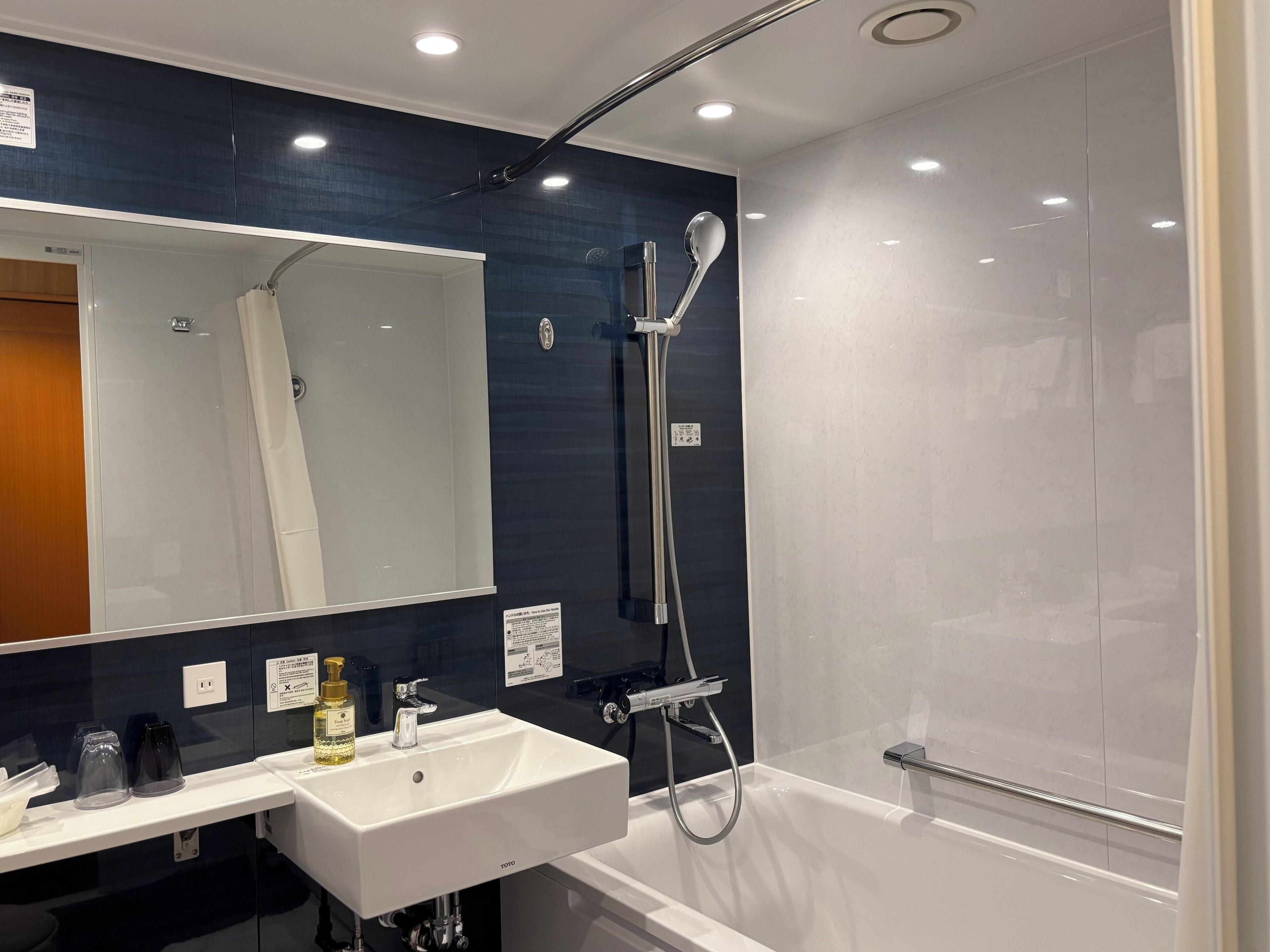 Un baño moderno con lavamanos, espejo y ducha blancos.