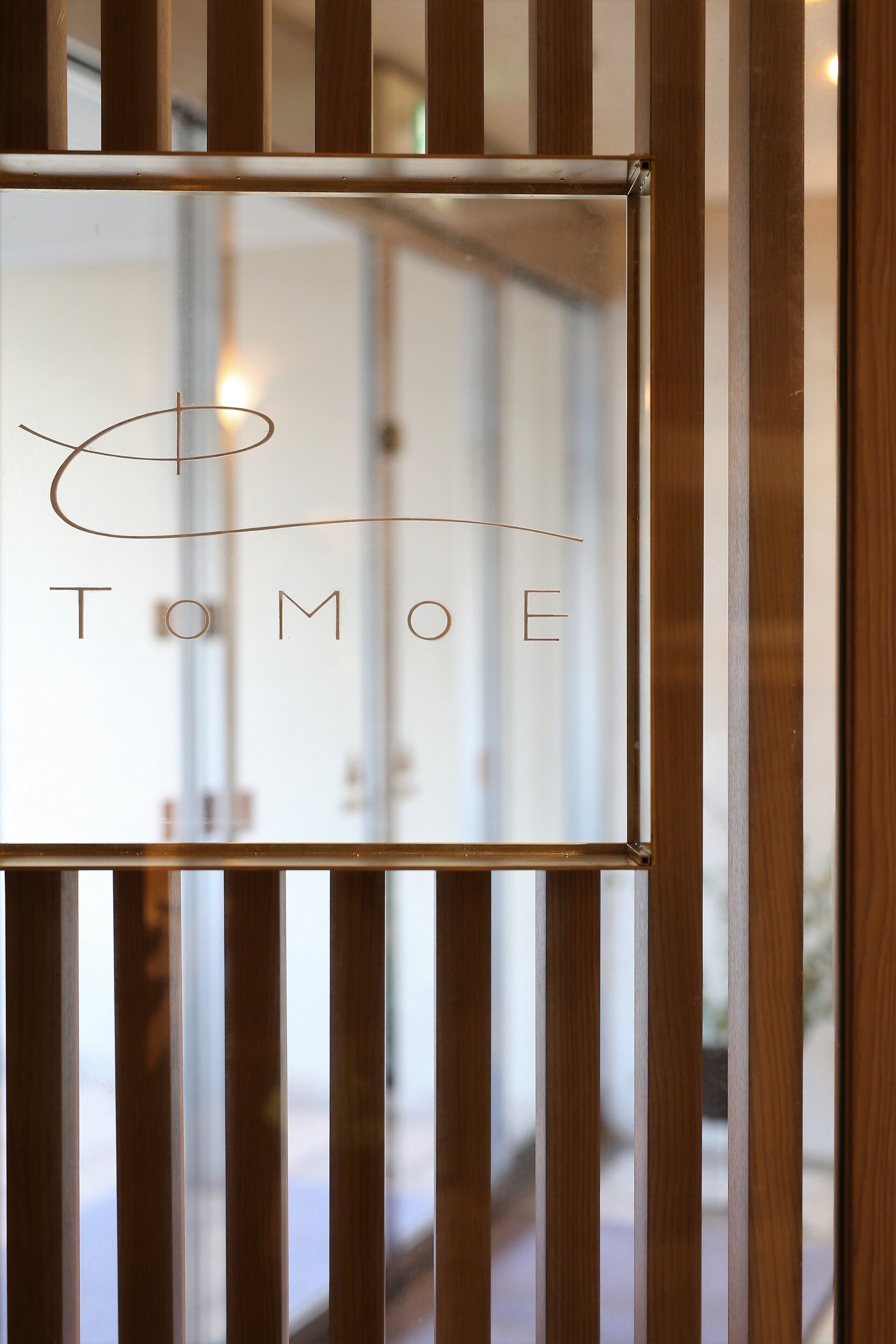 A framed sign with the name "TOMOE" on a wooden structure.