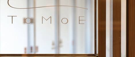 A framed sign with the name "TOMOE" on a wooden structure.