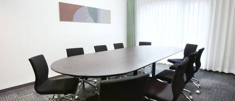 A conference room with a large table, black chairs, and a carpeted floor.