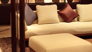 A modern living room with a sofa, ottoman, and a lamp. - Okayama Koraku Hotel (Okayama)