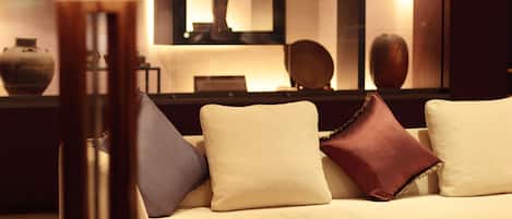 A modern living room with a sofa, ottoman, and a lamp.