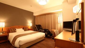 A hotel room with a large bed, a desk with a computer, a chair, and a TV.