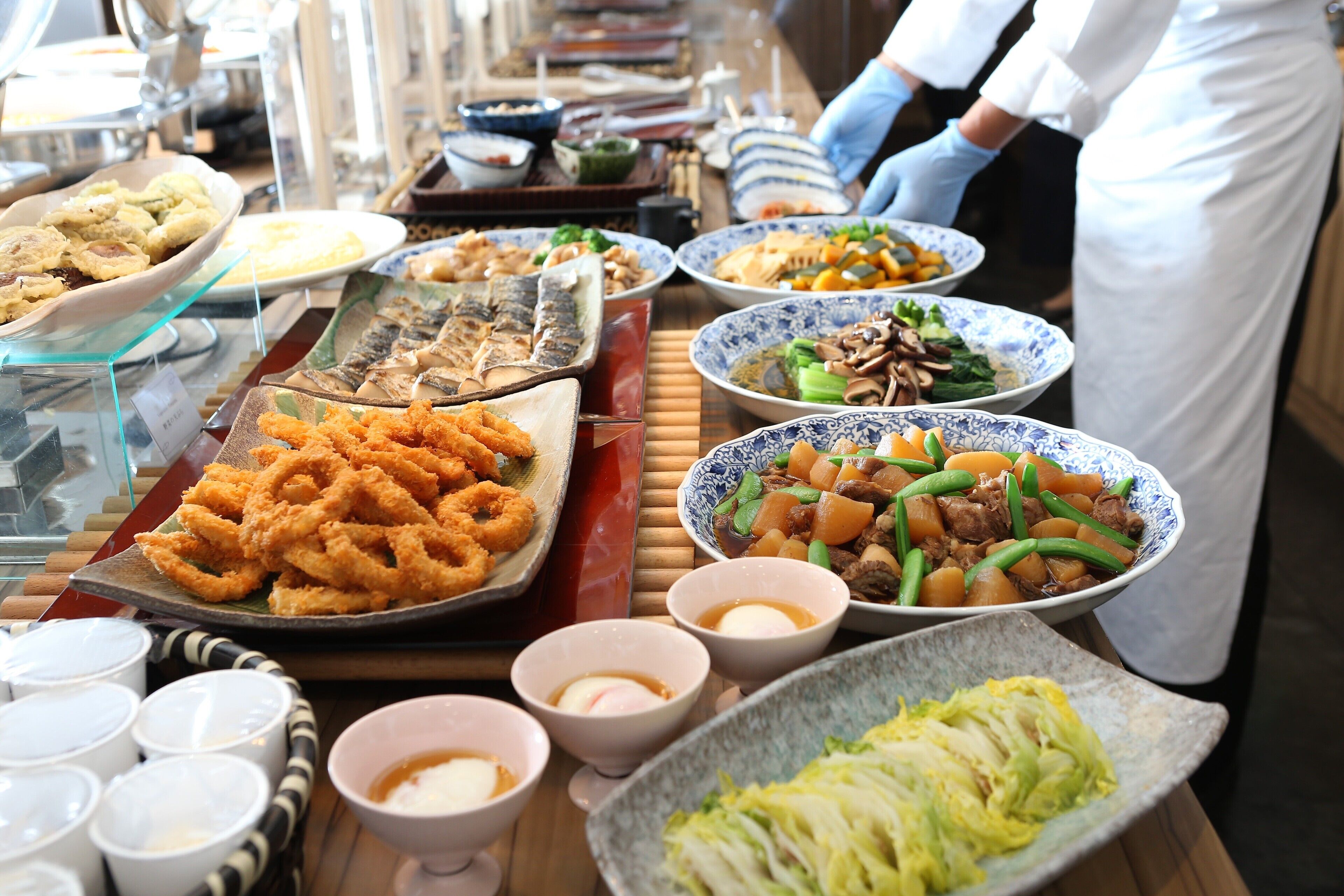 Un bufé con diversos platos, entre ellos mariscos, verduras y una variedad de salsas.