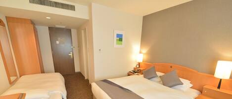A hotel room with two beds, a desk, and a nightstand with lamps.