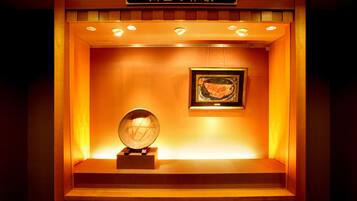 Eine Vitrine mit einem gerahmten Kunstwerk und einem Globus, beleuchtet von warmem Licht.