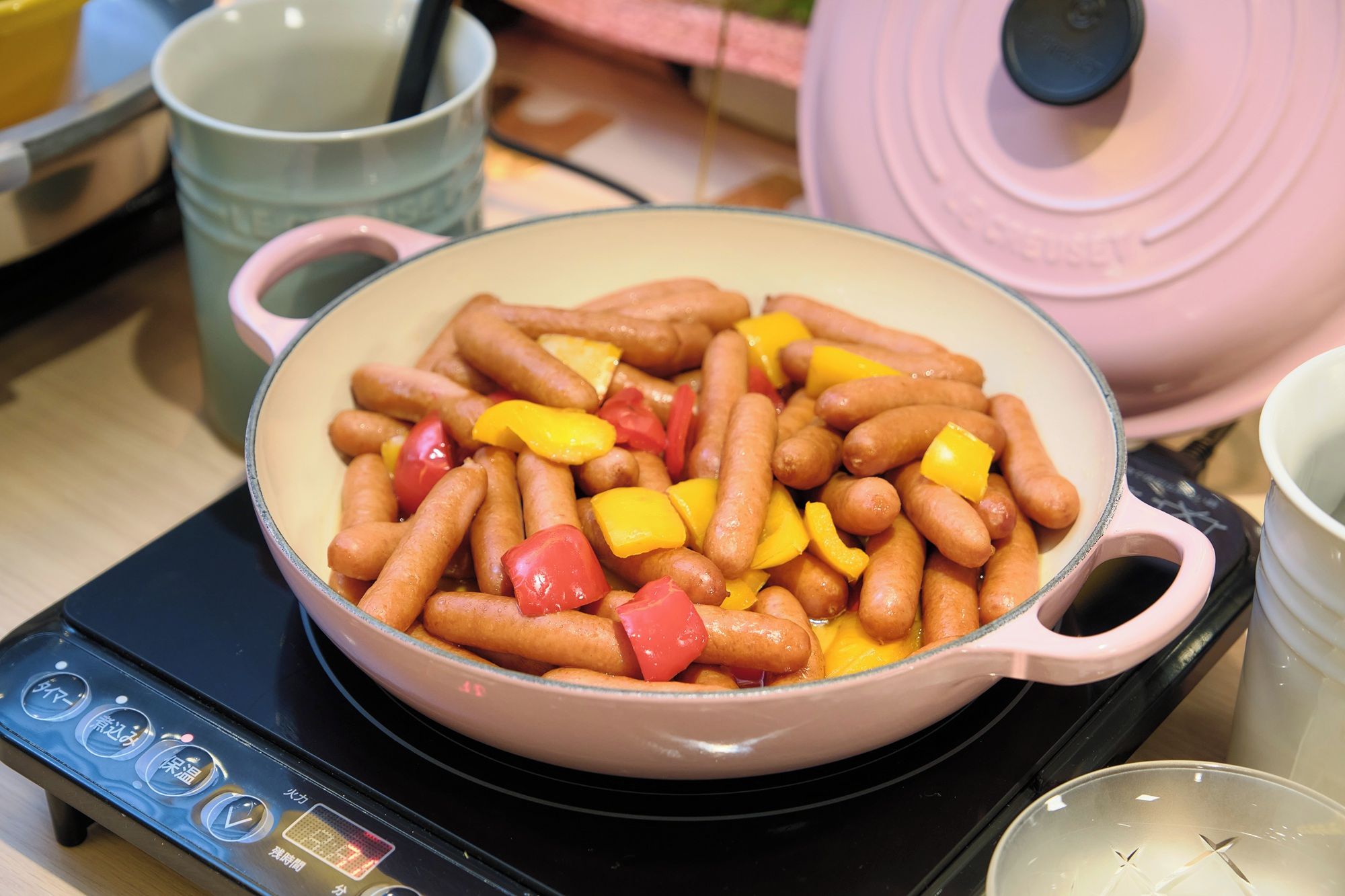 Una olla con salchichas y pimientos sobre una estufa.
