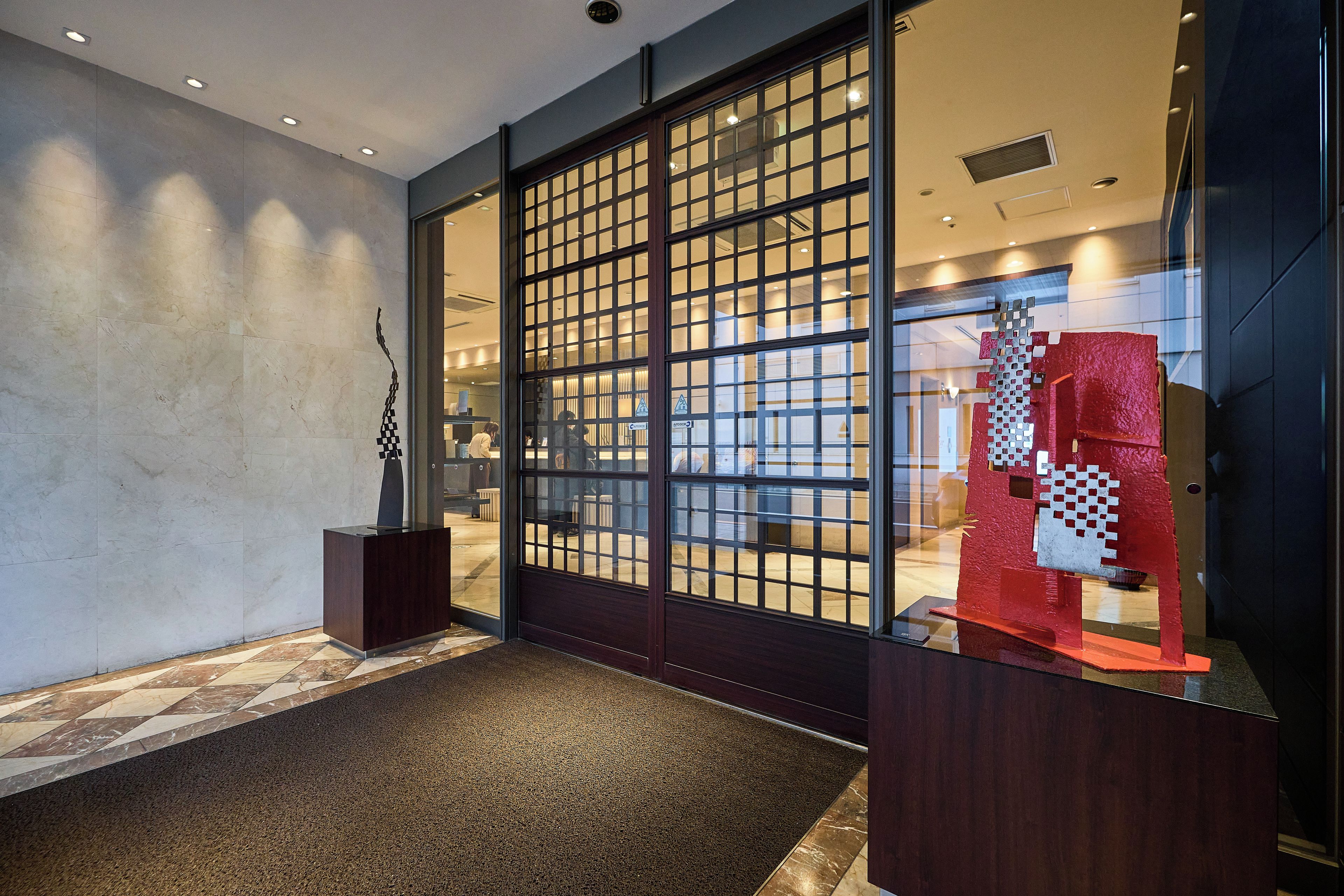 A reception area with a checkered floor, a reception desk, and a glass partition with a grid pattern.
