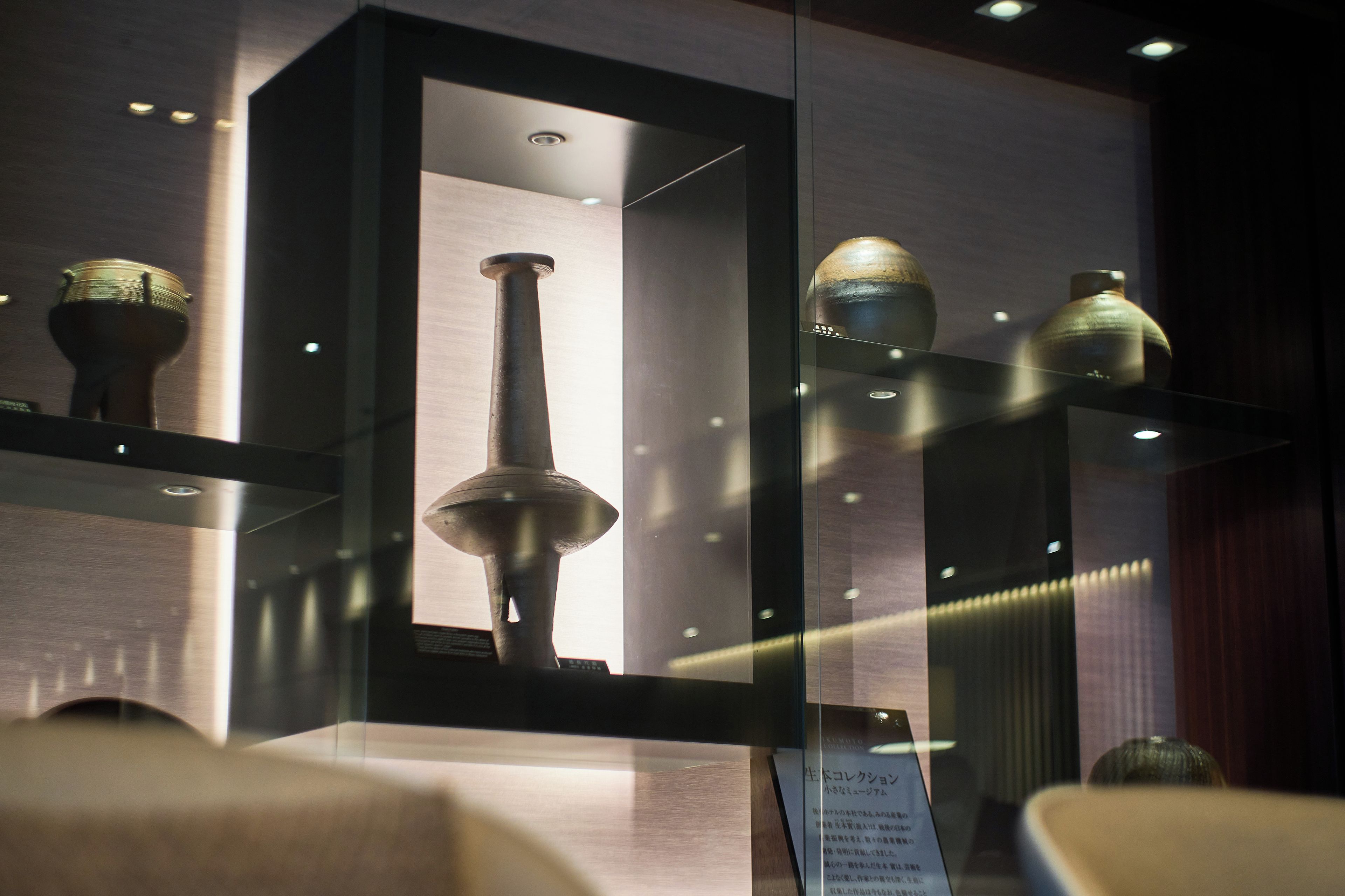 Une vitrine exposant divers objets historiques, notamment des poteries et un objet en métal, accompagnée d’un panneau explicatif.