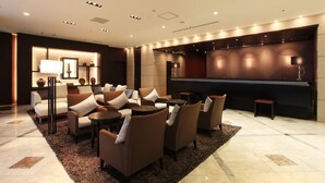 A modern lounge area with sofas, a piano, and a well-lit ambiance. - Okayama Koraku Hotel (Okayama)