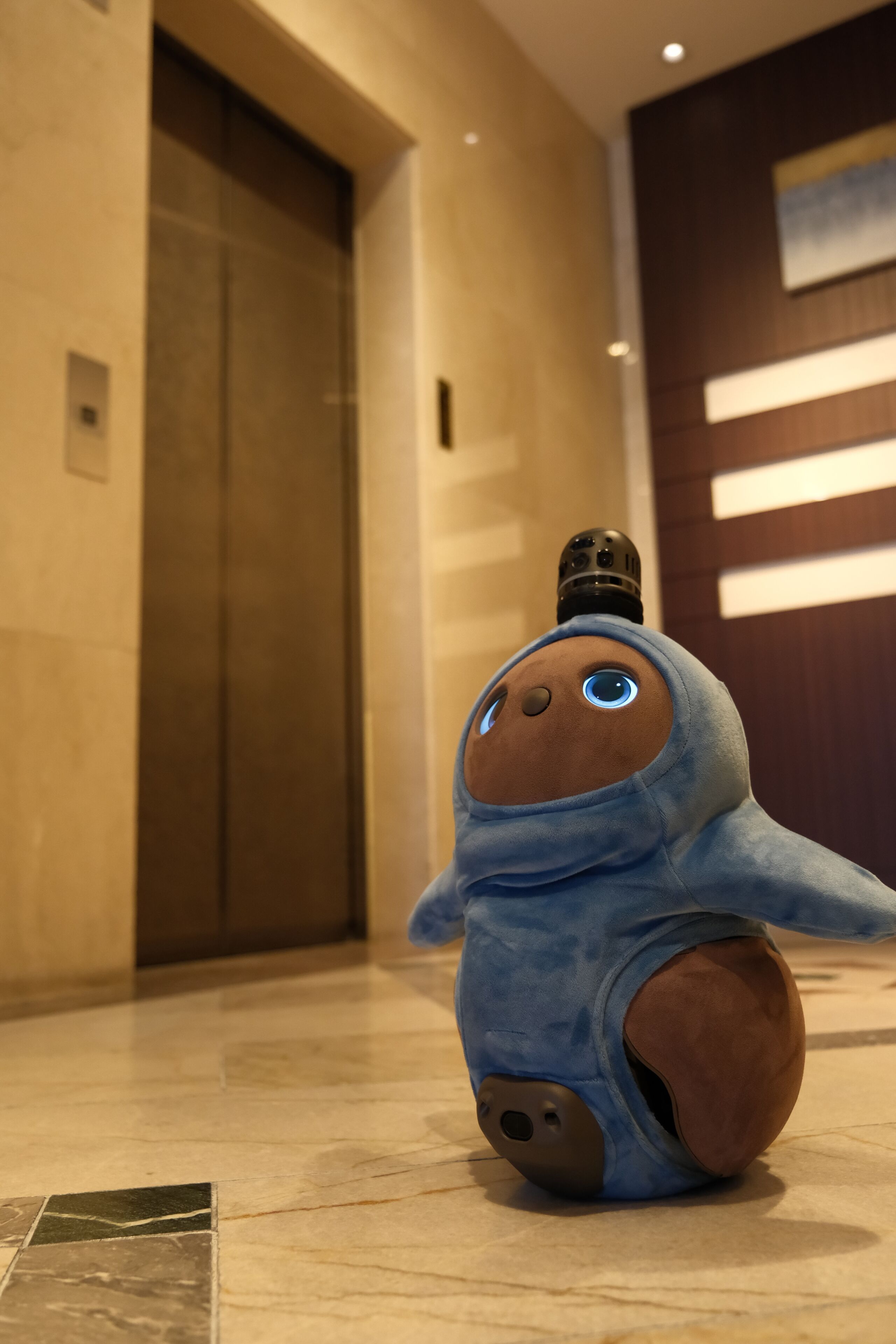 A plush toy in a lobby with a marble floor and a door in the background.