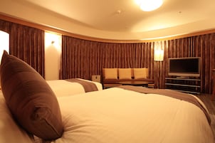 Una habitación de hotel con dos camas, televisión, escritorio y lámpara.
