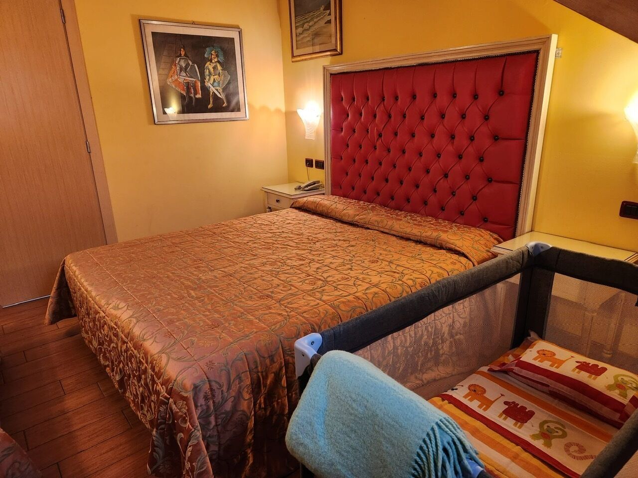 A bedroom with a large bed, a red headboard, a nightstand, and a chair.