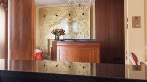 A reception desk with a wooden finish, a chandelier, and a wall clock. - Hotel Alle Torri (Mestre)