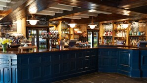 Un bar con una barra azul oscuro, una caja registradora y una variedad de botellas y vasos en estantes.