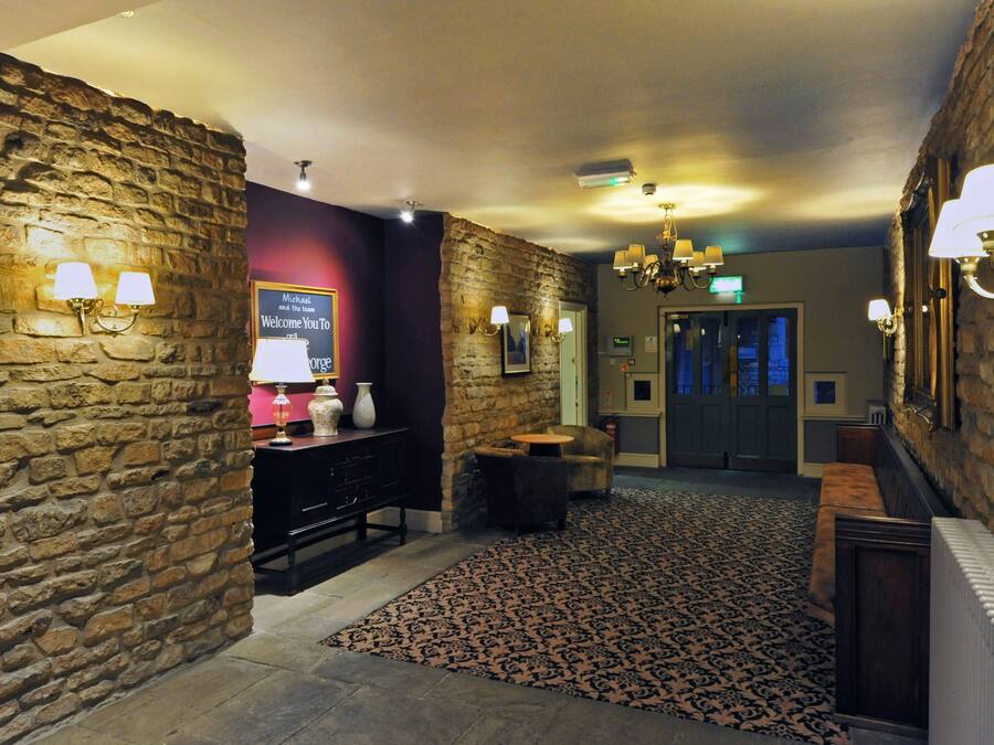 A lobby with stone walls, a reception desk, a chandelier, and a patterned carpet.