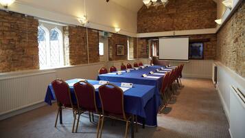A conference room with a long table, red chairs, and a projector screen.