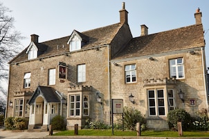 A stone building with a traditional architectural style, featuring multiple windows and a sign indicating the price for main courses.