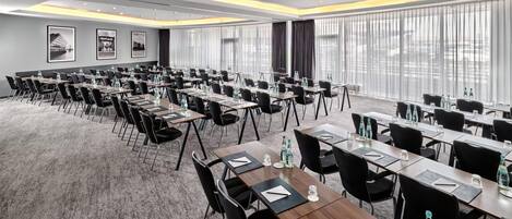 A conference room with multiple tables, chairs, and water bottles.