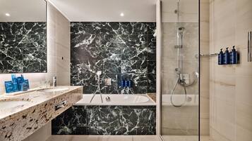 A modern bathroom with a marble vanity, a bathtub, and a glass-enclosed shower area.