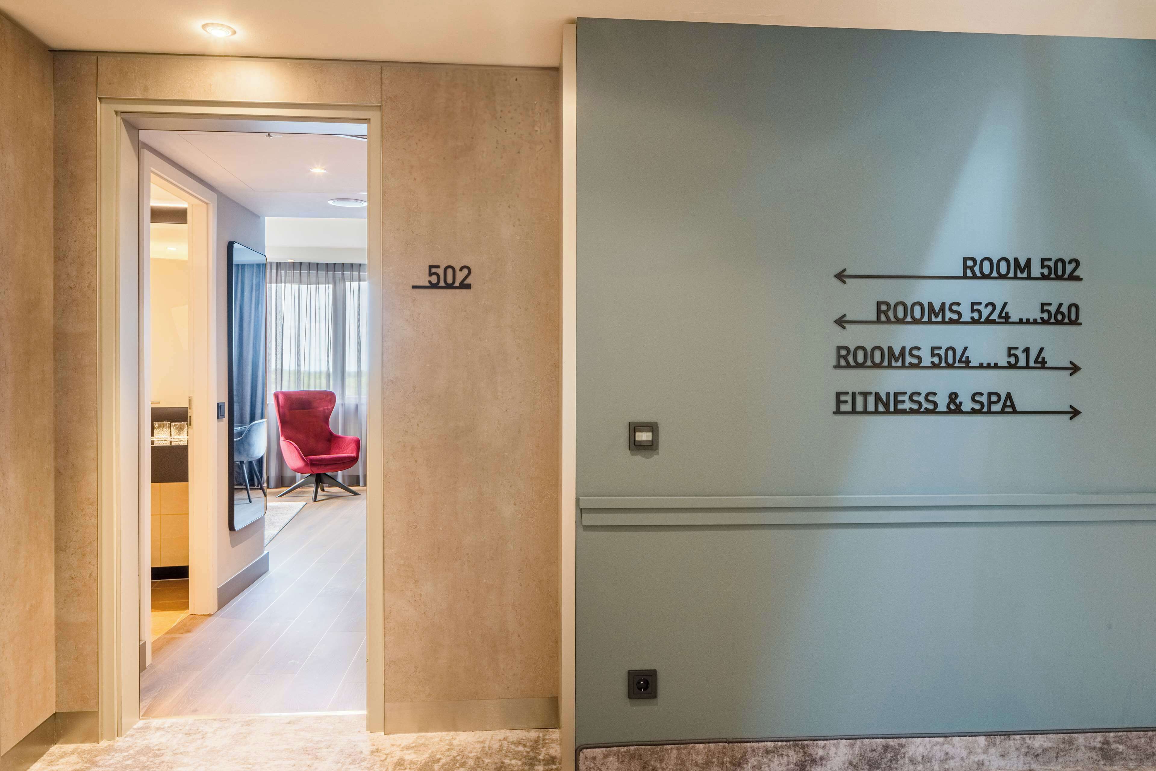 A hotel hallway with a sign indicating room numbers and a direction to the fitness and spa area.