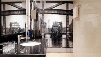 A bathroom with a large mirror, a sink, and a shower.