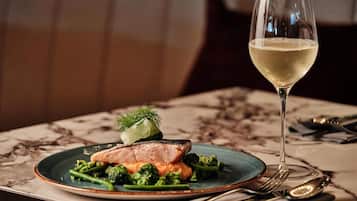 Un plato de comida con una copa de vino blanco sobre una mesa.