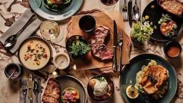 A well-set dining table with various dishes, including steak, soup, and bread, along with cutlery and glasses.