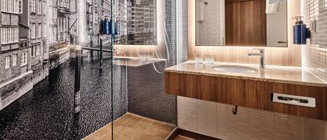 Un baño moderno con un espejo grande, un lavamanos y una ducha.