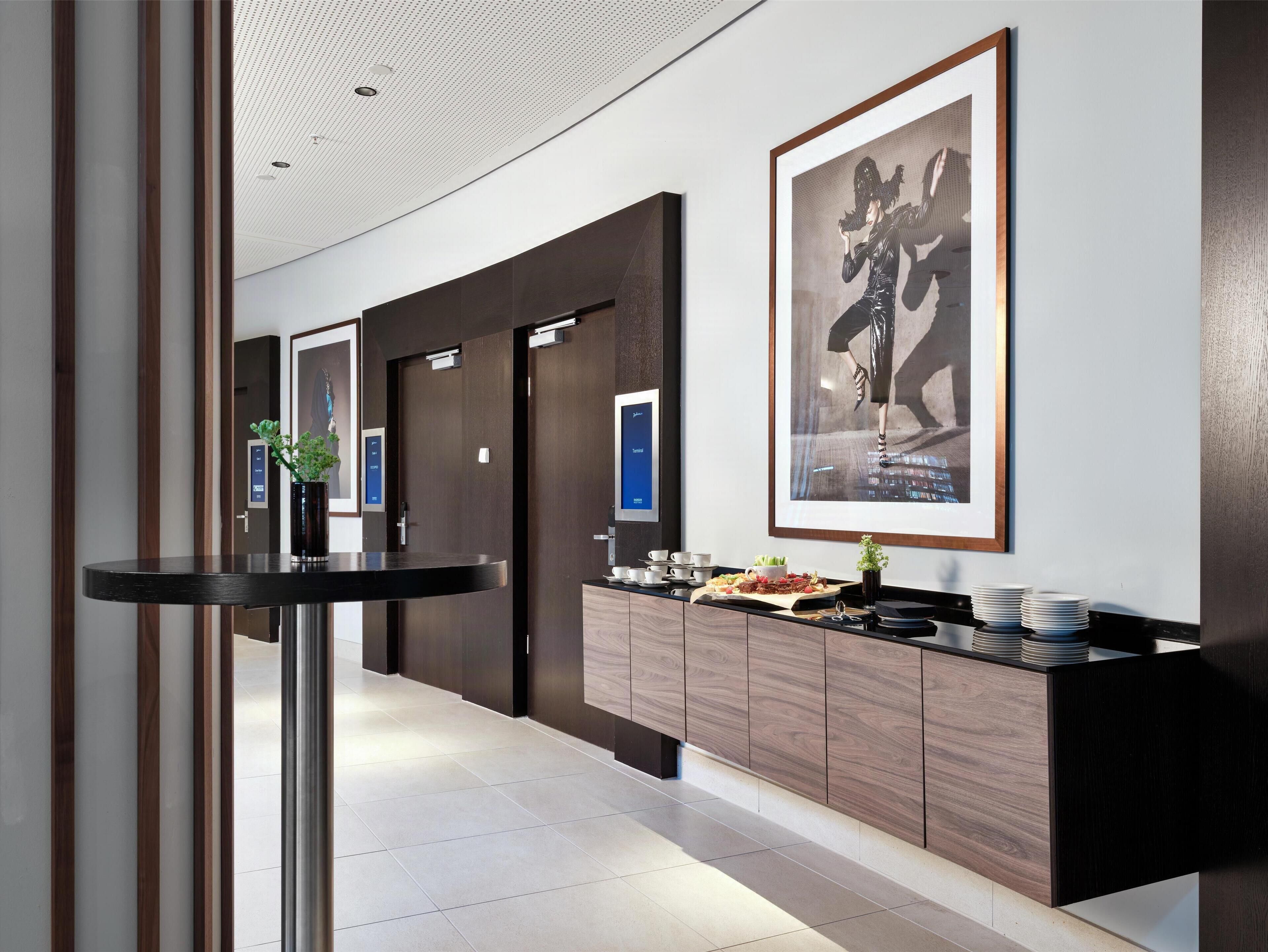 Un moderno vestíbulo de hotel con mostrador de recepción, obras de arte enmarcadas y zona de buffet.