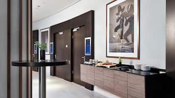 Un moderno vestíbulo de hotel con mostrador de recepción, obras de arte enmarcadas y zona de buffet.