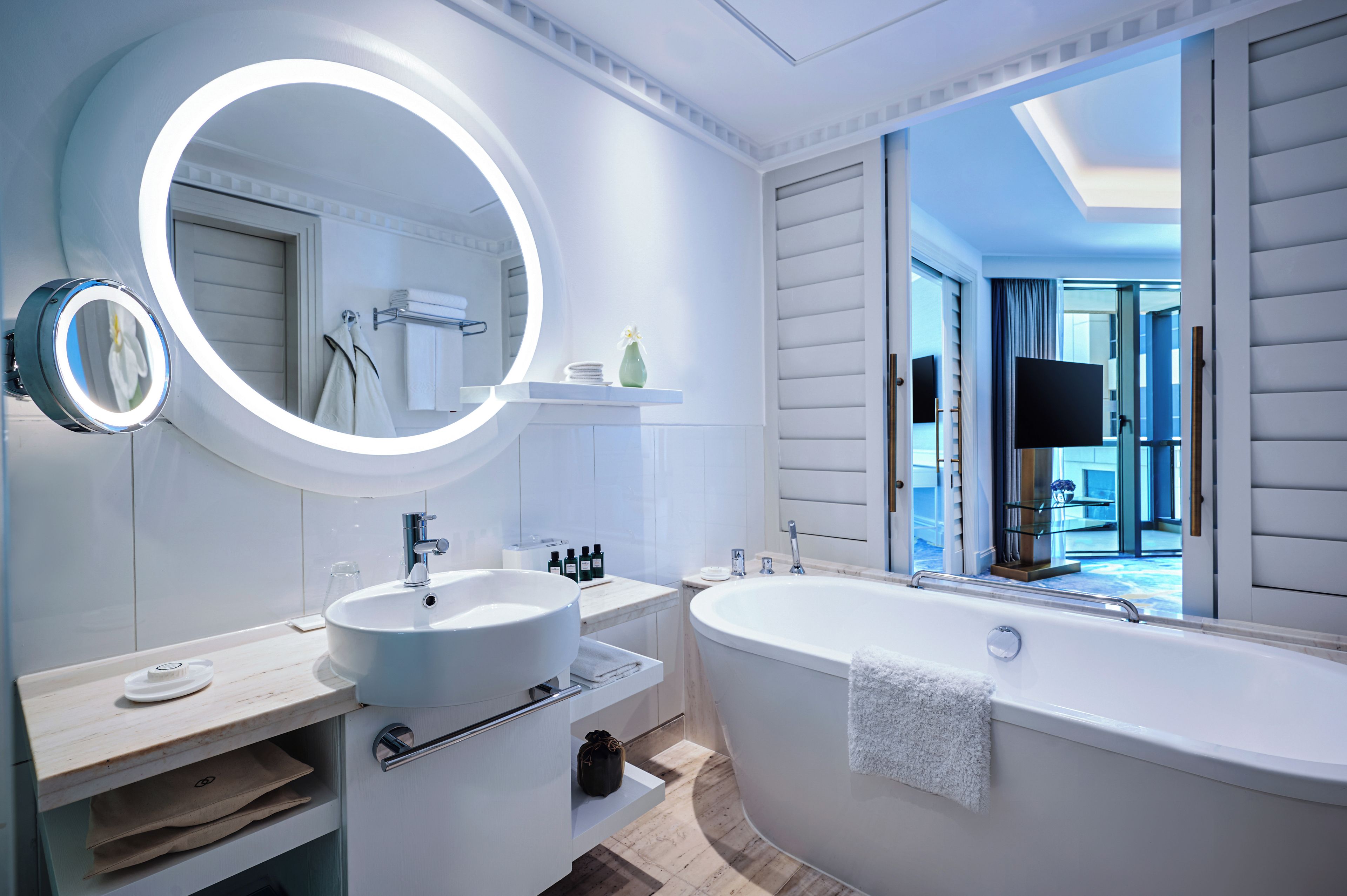 Un bagno moderno con uno specchio rotondo, un lavabo e una vasca da bagno freestanding.
