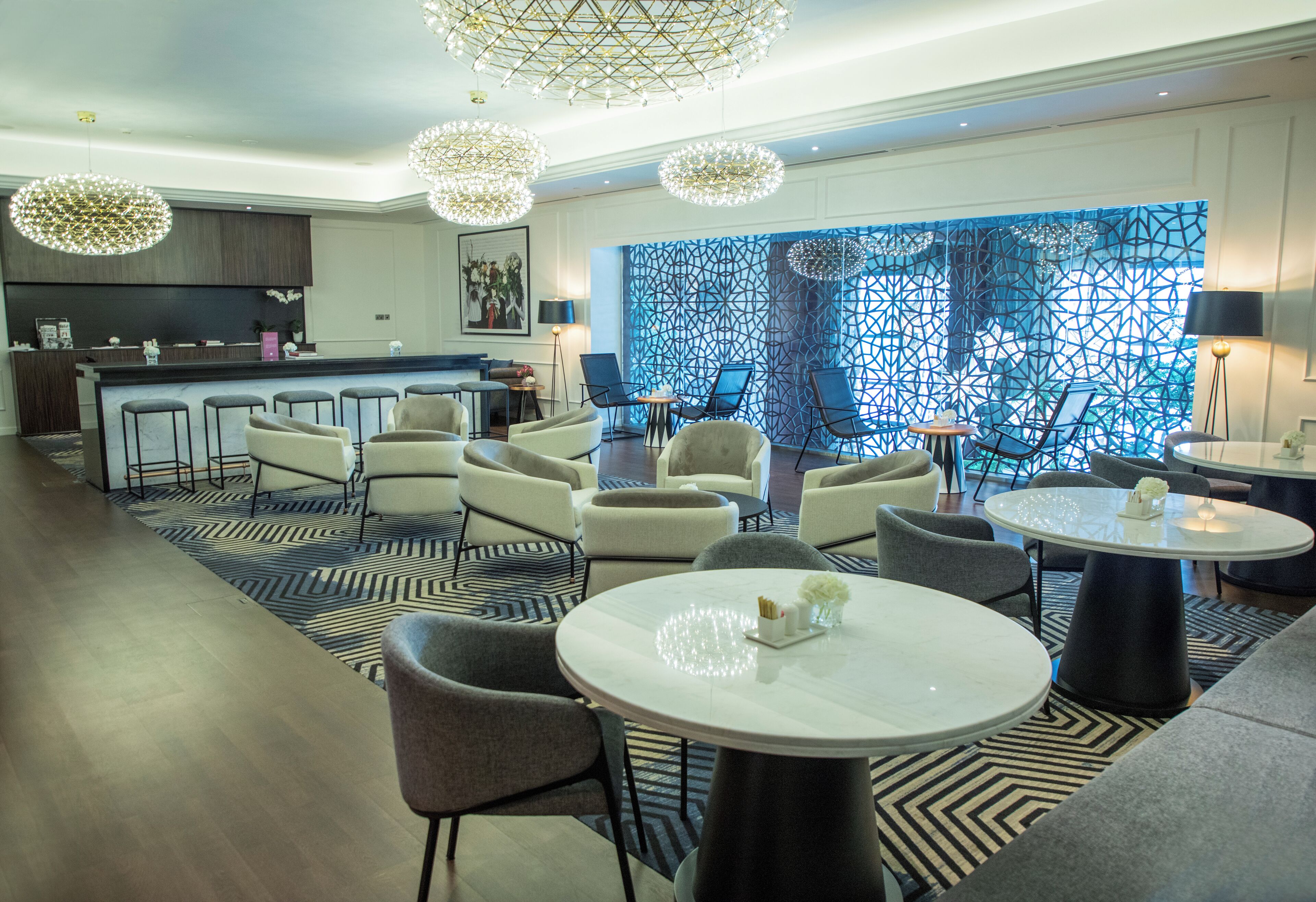 En modern hotellobby med en bar, en sittgrupp och en dekorativ vägg.