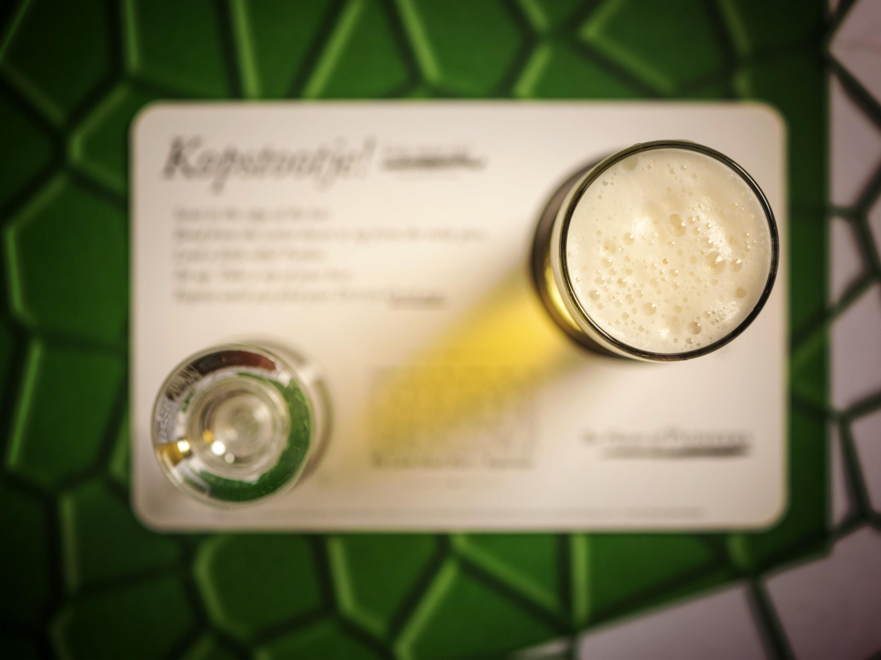 Un verre de bière posé sur un dessous de verre, avec un menu à côté.