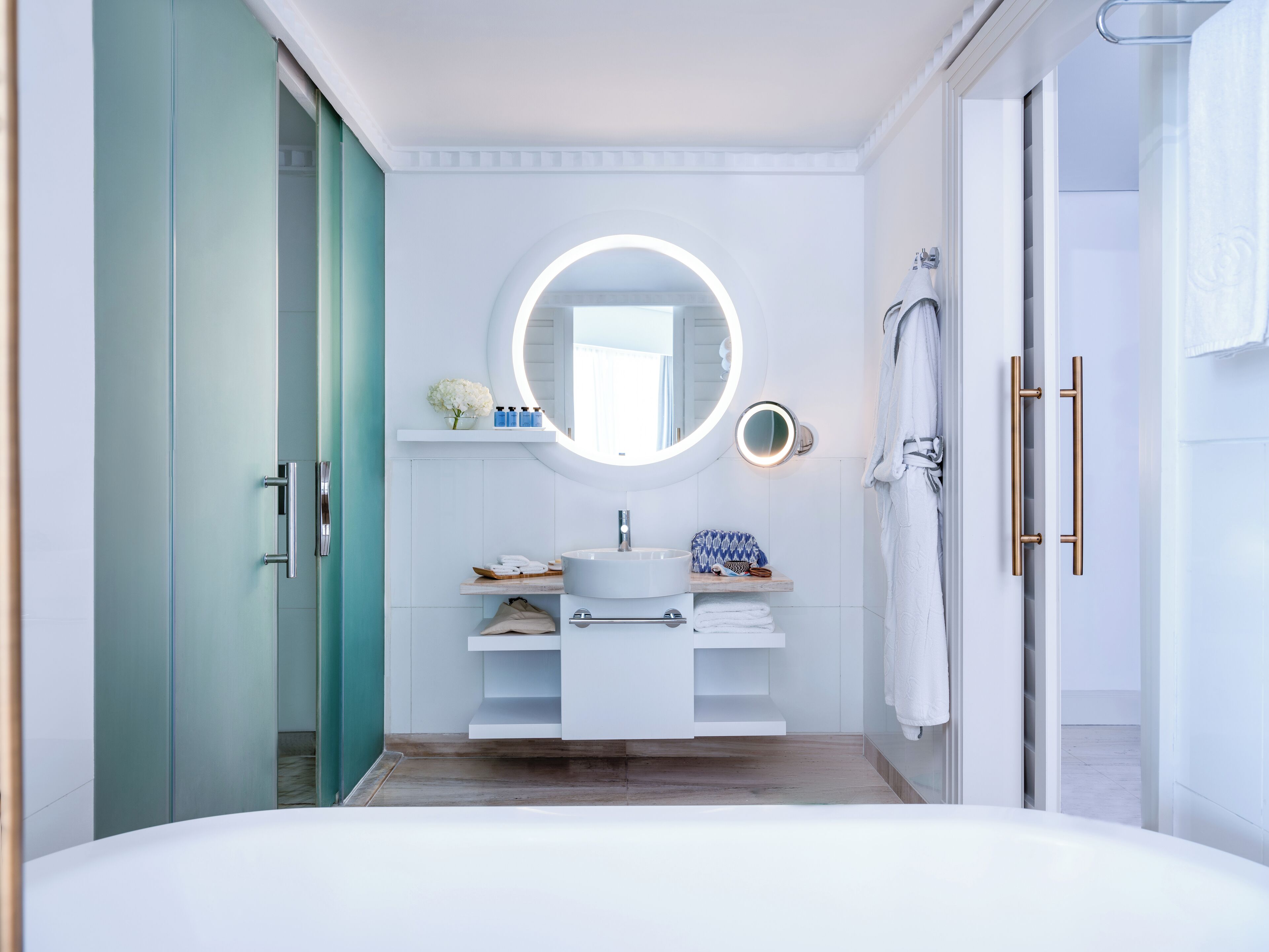 Een moderne badkamer met een ronde spiegel, een wit wastafelmeubel en een douchehoek.