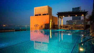 Una piscina con vistas al horizonte urbano al atardecer.