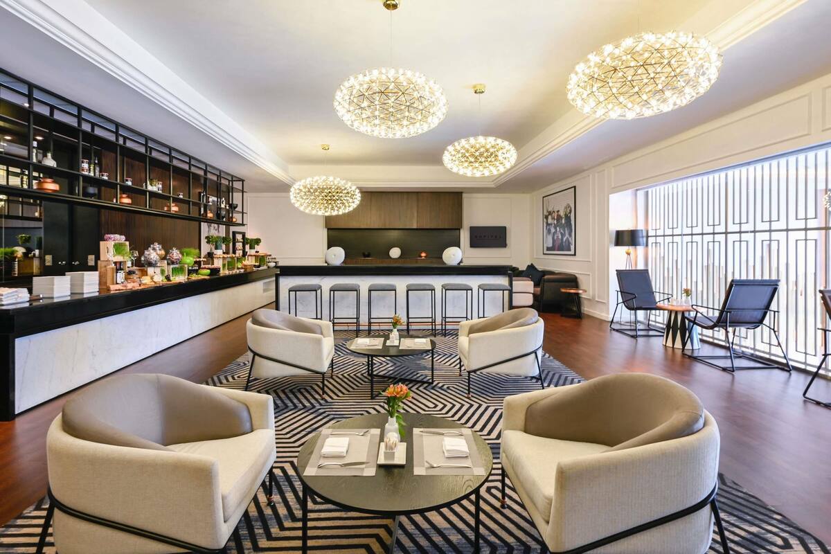 A modern hotel lobby with a bar, seating area, and large windows.