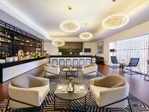 Un moderno vestíbulo de hotel con bar, zona de estar y amplias ventanas.