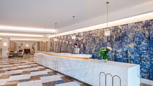 Eine moderne Hotelhalle mit einer Marmor-Rezeption, einem Check-in-Schalter und einem gemusterten Boden.