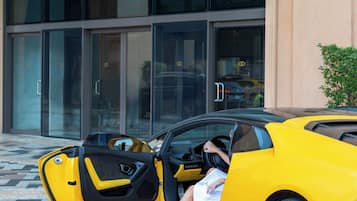 A yellow sports car parked in front of a building with a glass entrance.