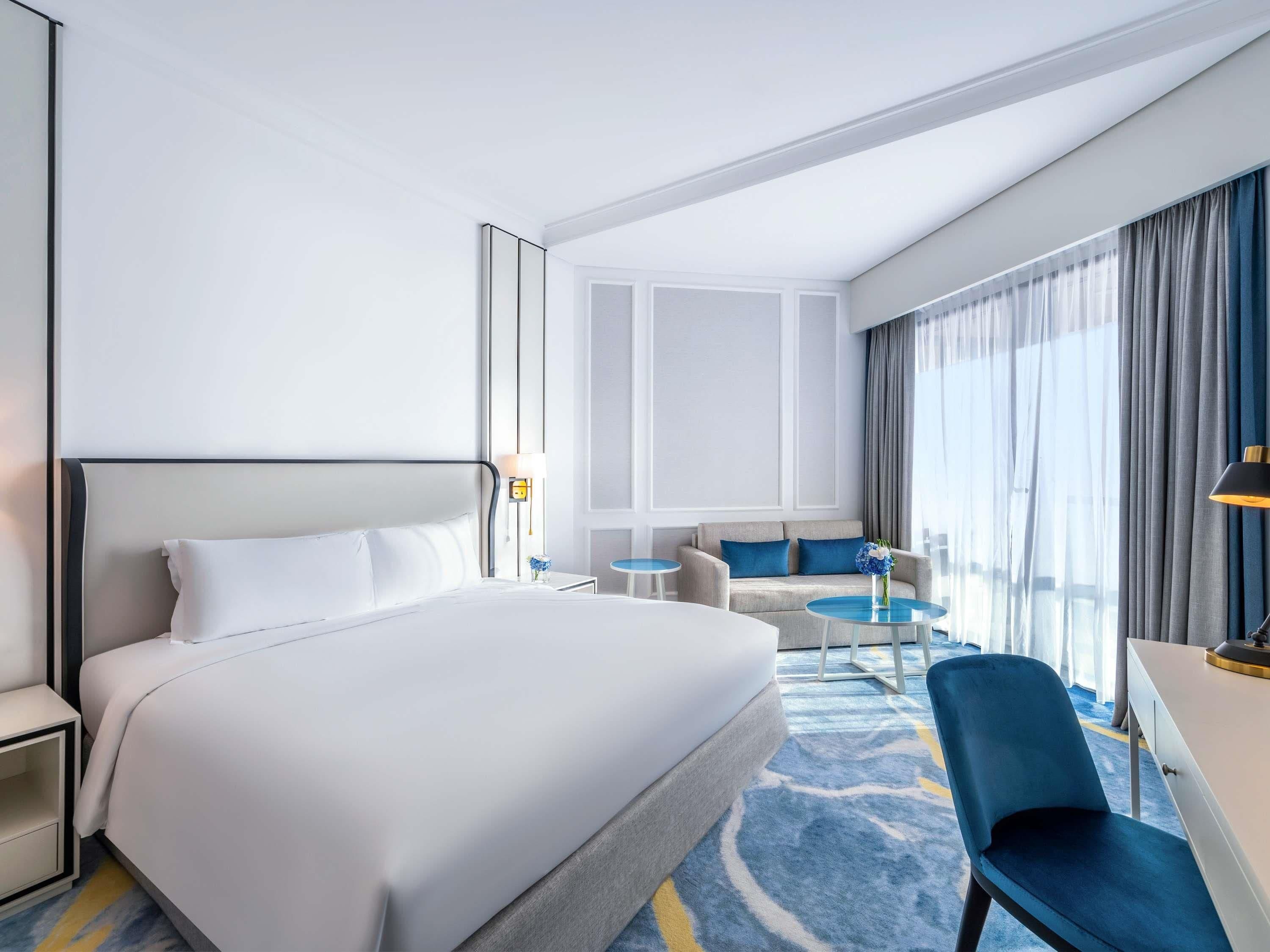 Une chambre d’hôtel avec un grand lit, un bureau, une chaise, un canapé et une petite table.