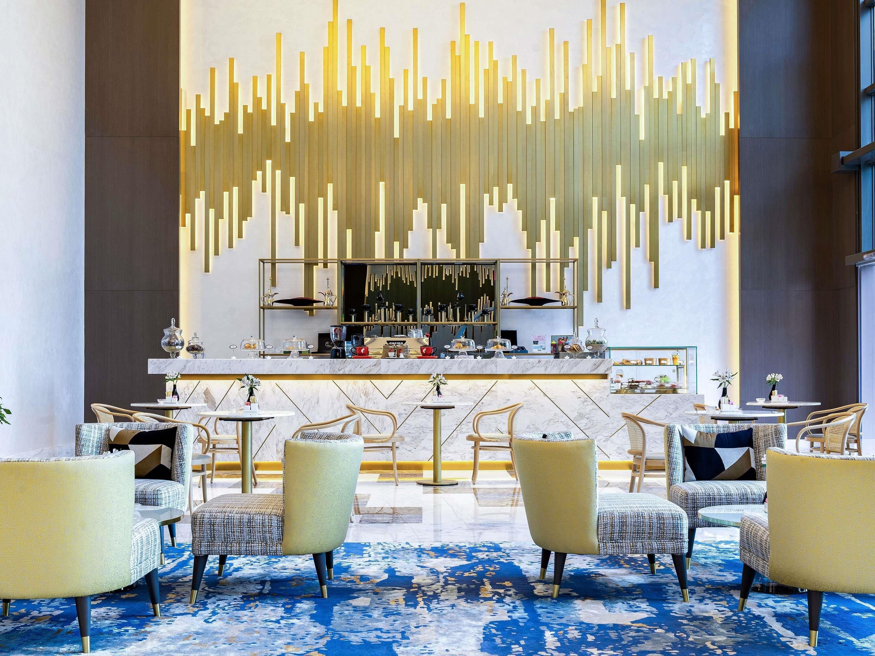 A modern bar area with a marble countertop, bar stools, and a decorative wall with vertical light fixtures.