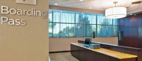 A modern reception area with a 'Boarding Pass' sign, a desk, and large windows.