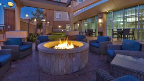 An outdoor patio area with wicker furniture, a central fire pit, and a glass-enclosed dining area. - Courtyard by Marriott Omaha La Vista (La Vista)