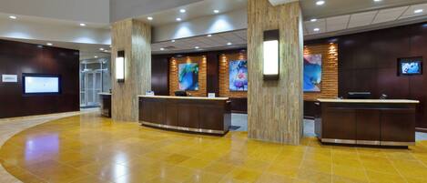 A hotel reception area with two reception desks, a curved yellow-tiled floor, and a modern interior design.