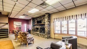 A lobby with a fireplace, seating area, and large windows.