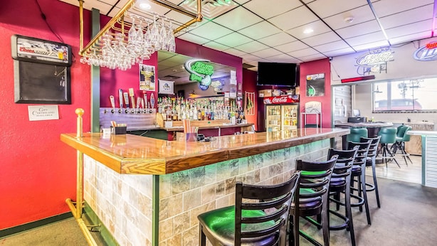 A bar area with a counter, stools, and a neon sign for Bud Light.