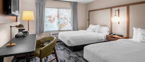 A hotel room with two beds, a desk, a chair, a TV, a lamp, and a window with curtains.