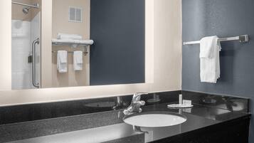 A modern bathroom with a large mirror, black granite countertop, and a white sink.