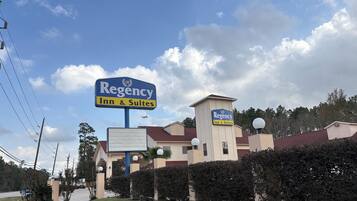 Et Regency Inn & Suites-bygning med et tydeligt skilt, omgivet af velholdt beplantning og en klar himmel.